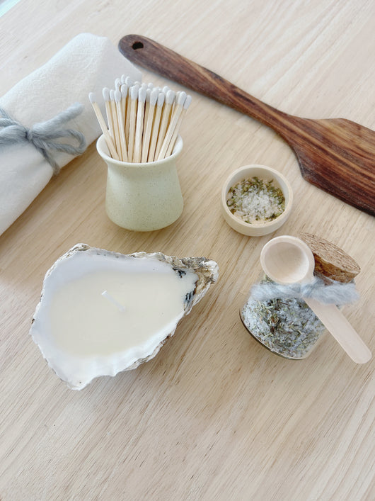 Collection of items including a shell, wooden spatula, and small containers on a light surface.